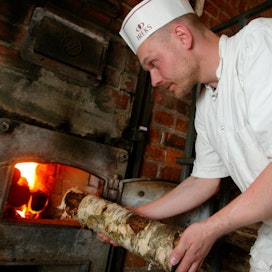 Pekka Heikkisen leipomossa ruisleipä paistetaan puulämmitteisessä uunissa. Leipuri Janne Kortelainen lisää koivuhalkoa pesään.