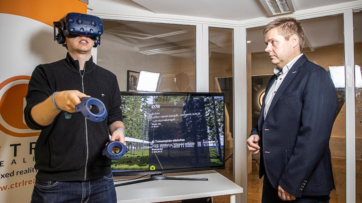 CTRL Realityn tuotepäällikkö Timo Korkalainen (vas.) tutustui virtuaalimetsään VR-lasien avulla. Toimitusjohtaja Teijo Lehtonen näki samalla ruudulta, missä päin palstaa liikutaan ja millaista metsän­hoitotoimenpidettä kuviolle ehdotetaan seuraavaksi.
