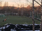 Helsinkiläisen pallokentän laidalla on lumikinoksia, jotka ovat mustuneita tekonurmen rengasrouheesta. Kuva kevättalvelta 2018.