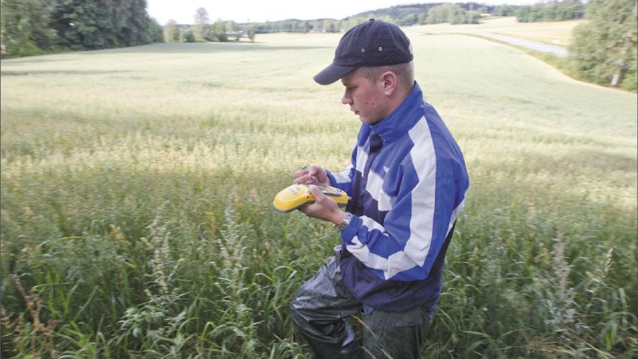 Samu Juvonen mittaa kartan mukaan epäselvän lohkorajan GPS-laitteella. Markku Vuorikari
