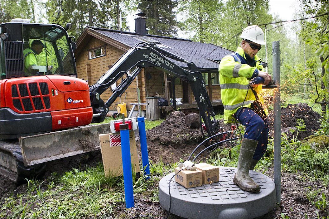 Vesiosuuskunnan puheenjohtaja Jukka Hietala leikkaa kiinteistökaivon ohjauskeskuksen asennusputkea poikki Mäntsälän Sääksjärvellä. Kari Salonen