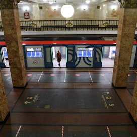 Matkustaja nousee Moskovassa metroon tyhjällä asemalla. Laiturin pinnassa on merkintöjä, joiden avulla voi huolehtia etäisyyden pidosta toisiin ihmisiin. LEHTIKUVA / AFP