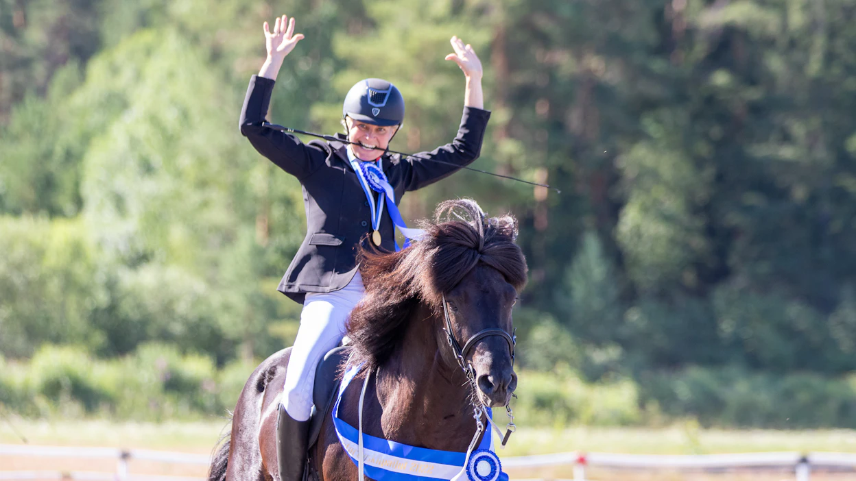 Jenni Kurki tuulettaa voittoaan ratsunsa Klókur frá Hveragerðin satulassa luokassa T2 vuoden 2022 SM-kisoissa. askellajiratsastus