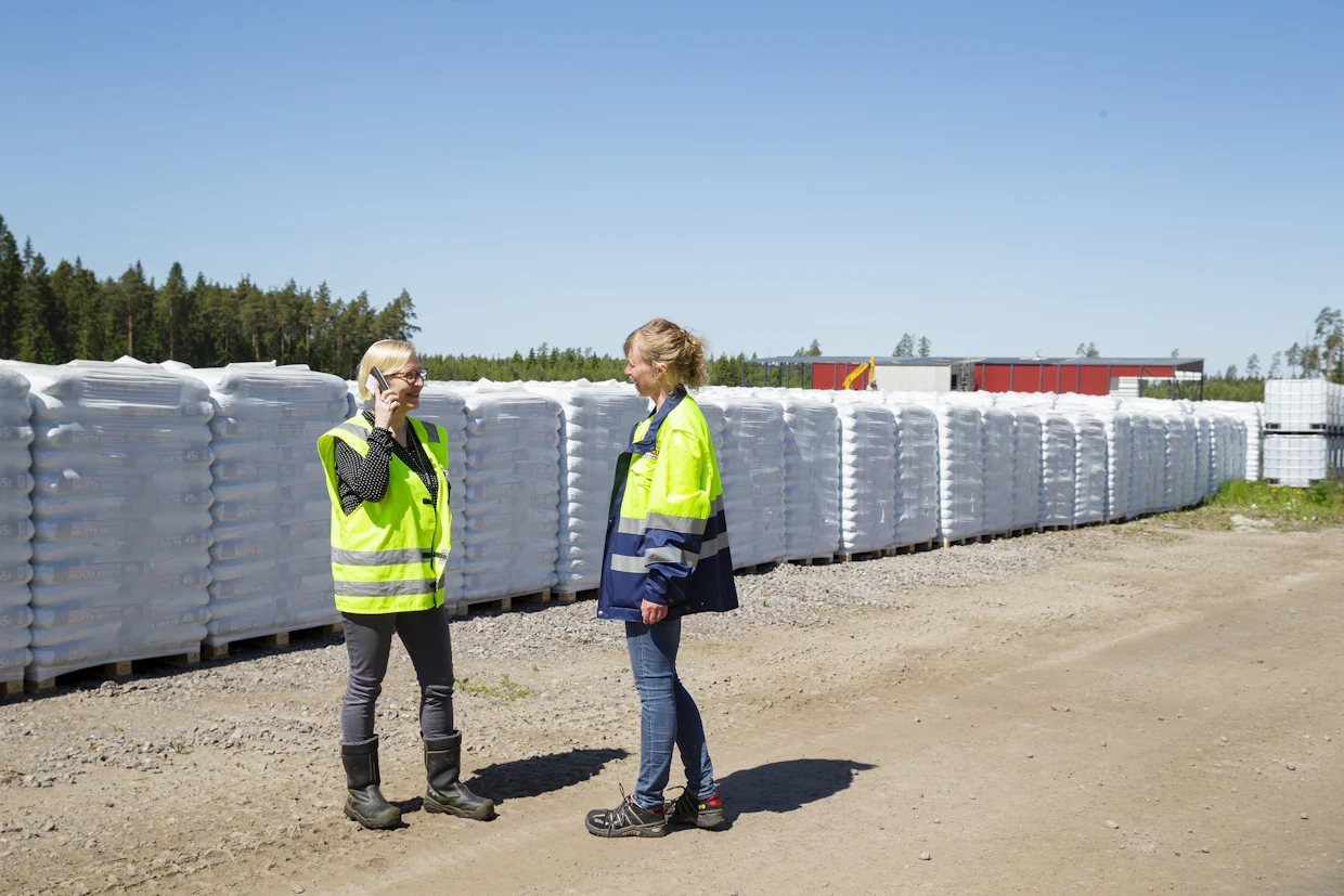 Valmista tavaraa lähdössä asiakkaille on silmänkantamattomiin. Säkkien takana siintää punaisena salaisuus: Biolanin syksyllä valmistuva biokuitulaitos. Kuvassa tuotekehitysjohtaja Hannamaija Fontell (vas.) ja puutarhaneuvoja Riikka Kerttula.