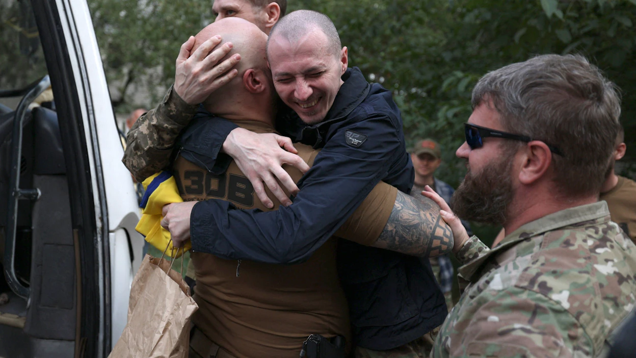 Sotavankeudesta vapautunut Ukrainan kansalliskaartin jäsen syleili perjantaina tovereitaan lähellä Ukrainan ja Valko-Venäjän rajaa. LEHTIKUVA / AFP .