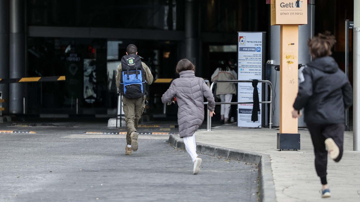Tel Avivissa ihmiset kiirehtivät suojaan hälytyssireenien soidessa lauantaina. LEHTIKUVA/AFP.