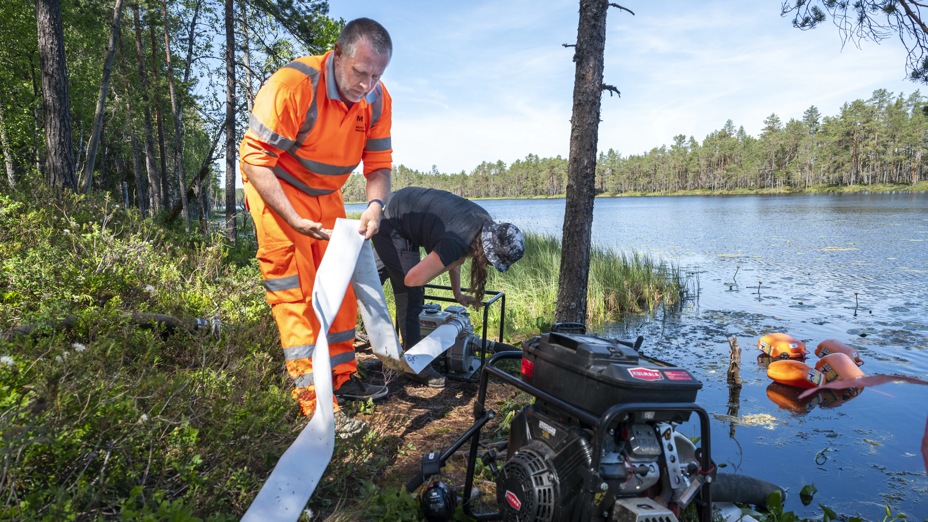 Komion luonnonsuojelualueella sammutusvesi saatiin johdettua polttokohteelle läheisestä järvestä. Kuvassa Markus Jaskari ja Helena Lundén asettelevat letkua paikalleen.