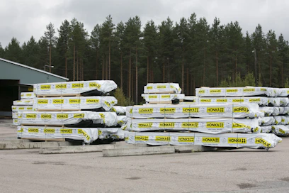 Honkarakenteen hirsipaketteja valmiina toimitettaviksi asiakkaille. Kuvituskuva.
