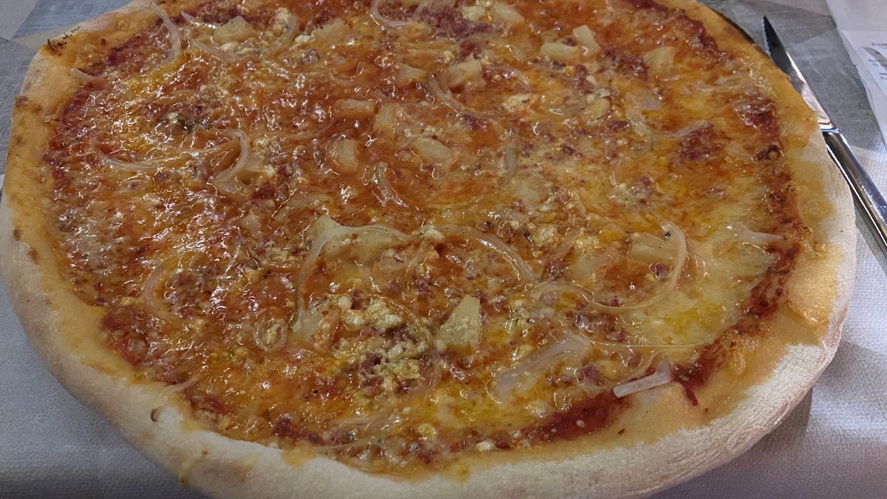 Eväskorin pizza on niin suuri, että se peittää alleen lautasen, mikä sekään ei ole kovin pieni.