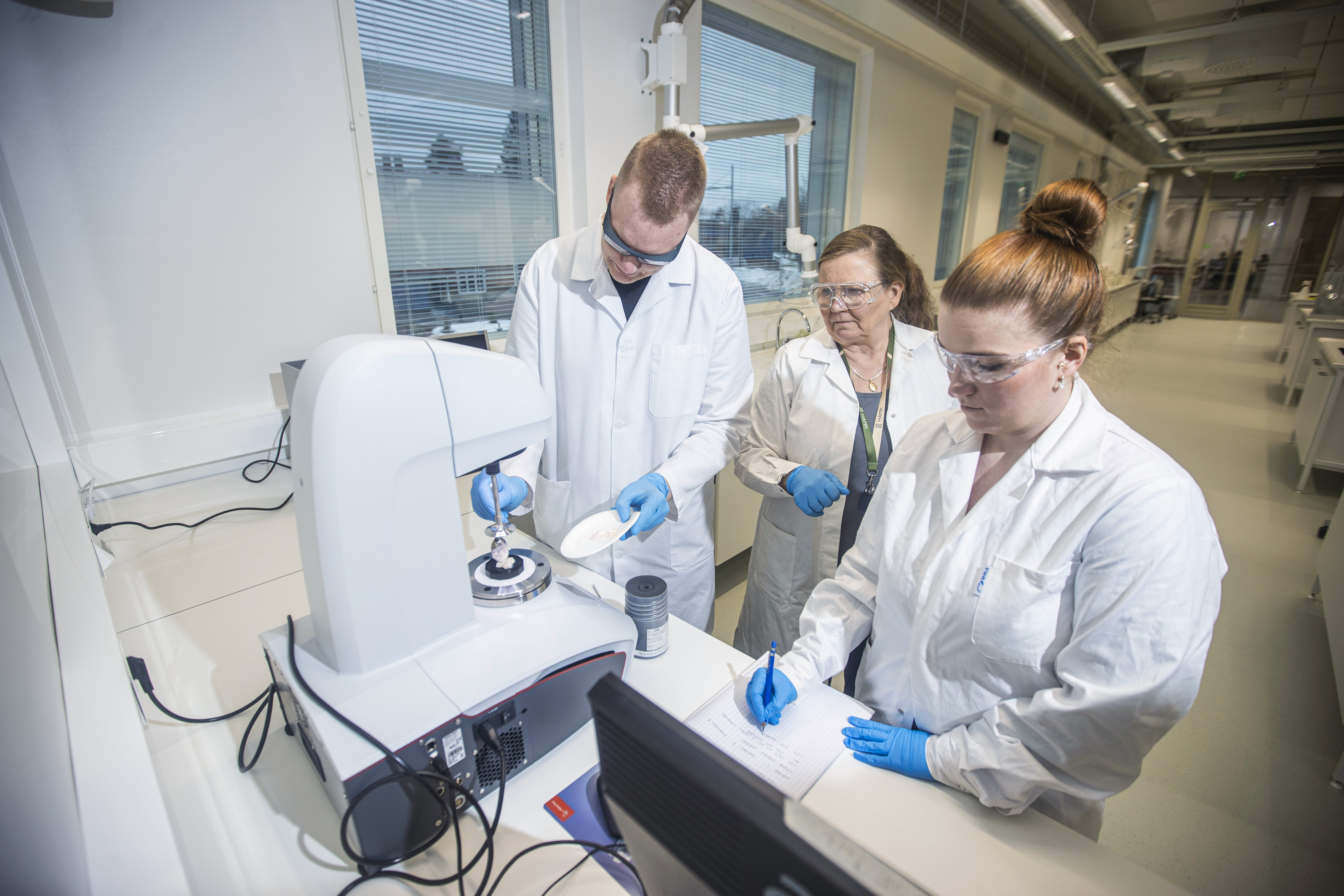 Lehtori Marja Allén (kesk.) neuvoo Sini Nymania ja Jere Ahokasta HAMK:n uudessa laboratoriossa. 