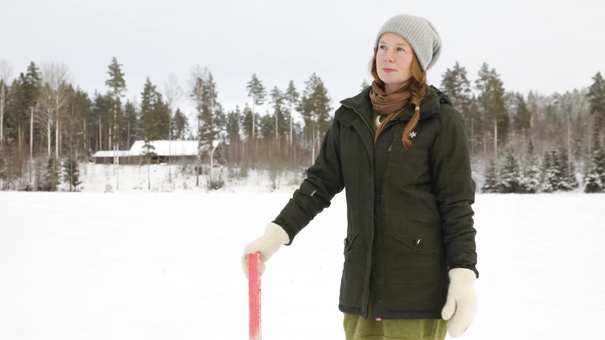 Niina Hosionaho seisoo aukealla, jonka keskeltä porhaltaisi vielä tällä vuosikymmenellä juna. Kotitalo näkyy taustalla.