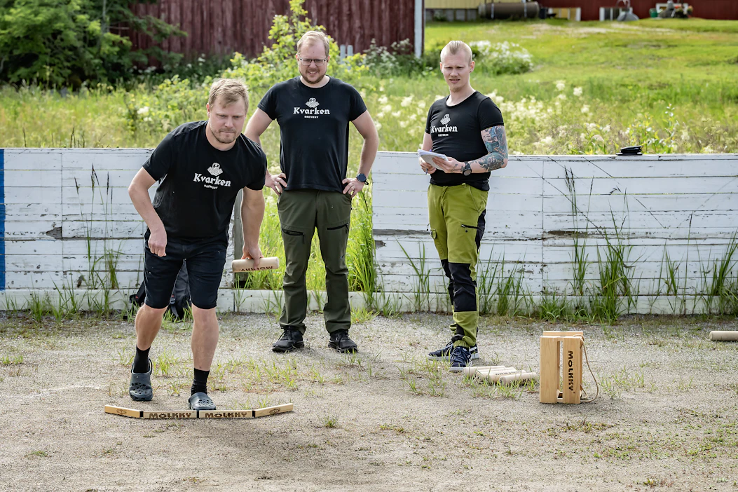 Kokenut mölkkykisailija Jussi Mäkelä keskittyy suoritukseen. Jarmo Mäkelä ja Ville Toivonen tarkkailevat taustalla. He ovat sonnustautuneet joukkueen yhteistyökumppanina toimivan paikallisen pienpanimon t-paitoihin.
