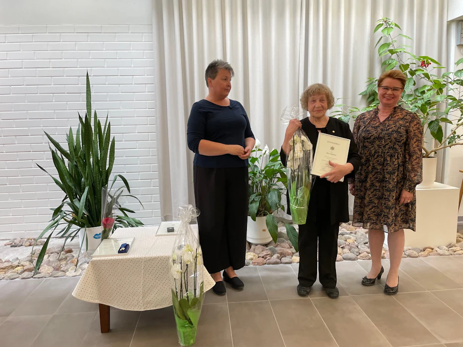 Pirjo Ropponen vastaanotti kultaisen kunniamerkkinsä Leppävirran kulttuuri- ja vapaa-aikalautakunnan puheenjohtaja Tiina Nousiaiselta (oik.) ja kulttuuri- ja vapaa-aikajohtaja Ann-Mari Karviselta.