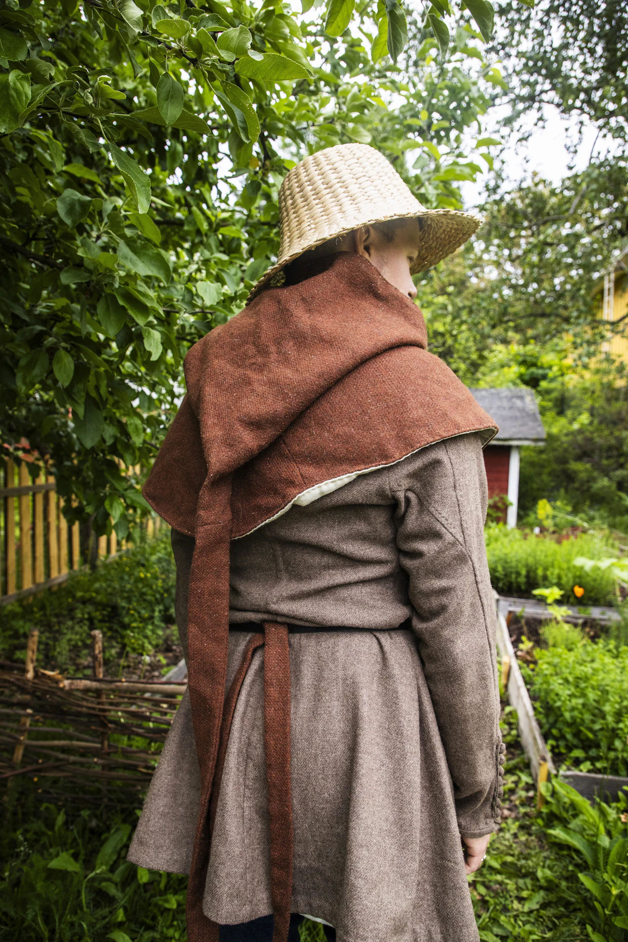 Häntähupun hännän voi kietoa kylmällä kaulan ympärille lämmittämään. Malli on 1300-luvun jälkipuoliskolta. Päässä on ruokohattu.
