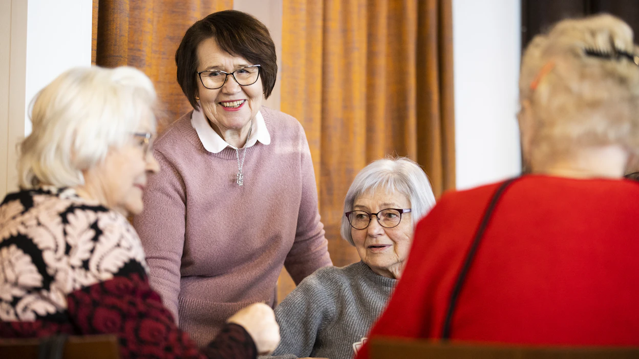 Riitta Ilola-Seppälä vetää Ystäväpiiri-toimintaa ikäihmisille Hauhon seurakuntatalolla. Pöydässä keskustelevat Pirkko Maula (vas), Riitta Ilola-Seppälä, Maire Valkama ja oikealla selin Ellen Pirinen.
