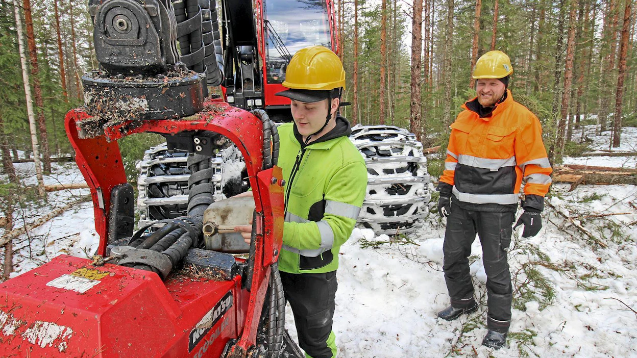 Kesän kynnyksellä hakkuukoneen kuljettajaksi valmistuva Elias Kirjavainen lisäsi teräketjuöljyä harvesteripään säiliöön Pasi Kilpeläisen valvovan silmän alla.