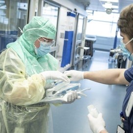 Suojapukuun pukeutunut hoitaja ja avustava hoitaja koronapotilaiden testaamiseen ja hoitoon tarkoitetulla osastolla Turun yliopistollisessa keskussairaalassa.