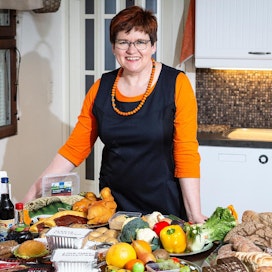 Maa- ja kotitalousnaisten järjestöpäällikkö Helena Velin esittelee pöytää, johon on koottu suomalaisen vuodessa kotonaan hukkaama ruoka.