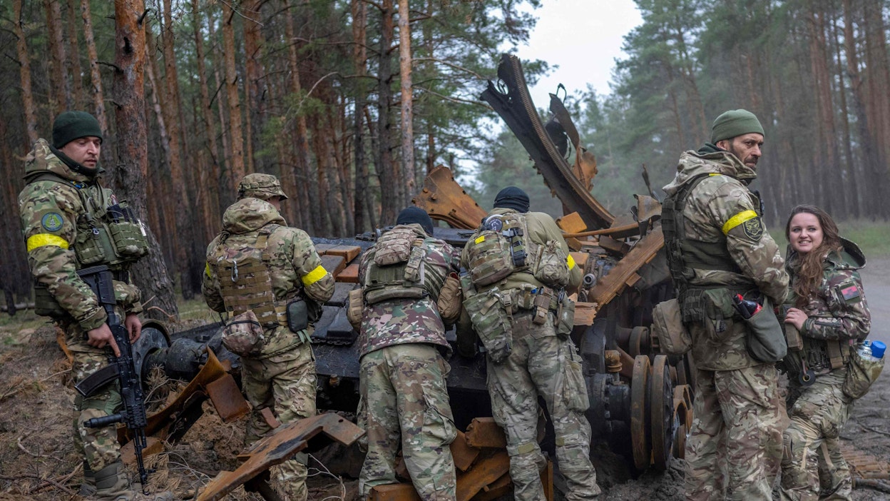 Ukrainalaiset sotilaat ja vapaaehtoistaistelijat tutkivat tuhottua Venäjän tankkia paikassa, jonka sijaintia ei kerrottu.