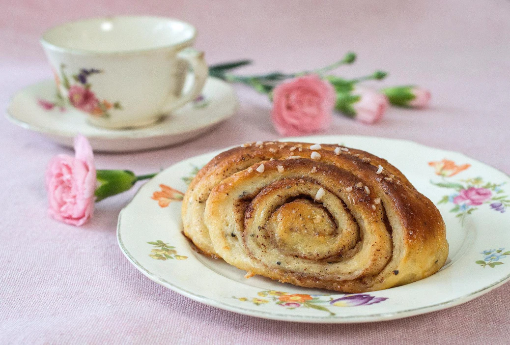 Tuore korvapuusti reilulla kaneli-sokeri-voitäytteellä maistuu kahvin tai kylmän maidon kanssa.