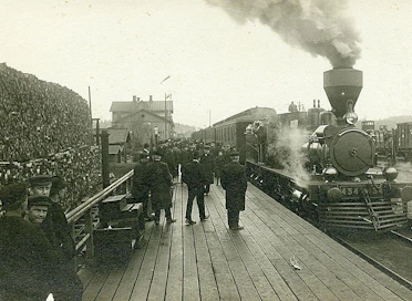 Riihimäen rautatieasema.  Aseman edessä laiturilla matkustajia ja raiteella höyryveturi Sk3, nro 434. Kuva on arviolta vuodelta 1907.