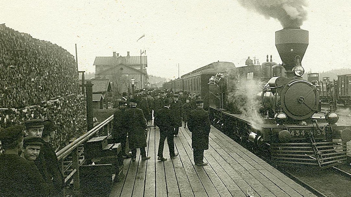 Riihimäen rautatieasema.  Aseman edessä laiturilla matkustajia ja raiteella höyryveturi Sk3, nro 434. Kuva on arviolta vuodelta 1907.