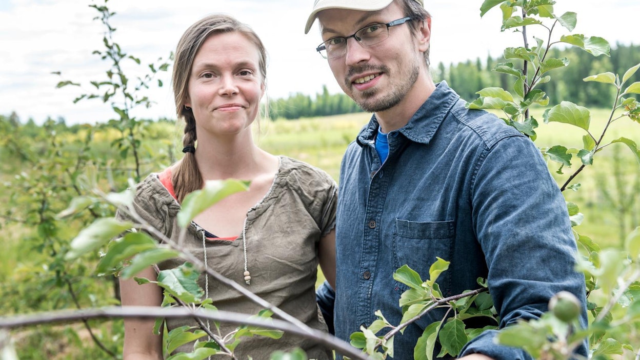 Iiris ja Tuomas Mattila omenatarhassa, joka on istutettu suojaamaan jyrkkää peltolohkoa eroosiolta.