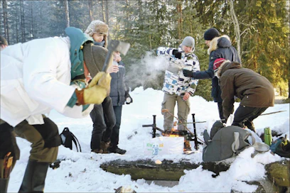 Kansainvälisiä opiskelijoita Itä-Suomen yliopistossa luotsaava amanuenssi Markku Ropo näyttää etualalla, kuinka tervasrosomännystä syntyy sytykettä, taustalla jo lämmitellään nuotiolla. Lari Lievonen
