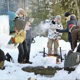 Kansainvälisiä opiskelijoita Itä-Suomen yliopistossa luotsaava amanuenssi Markku Ropo näyttää etualalla, kuinka tervasrosomännystä syntyy sytykettä, taustalla jo lämmitellään nuotiolla. Lari Lievonen
