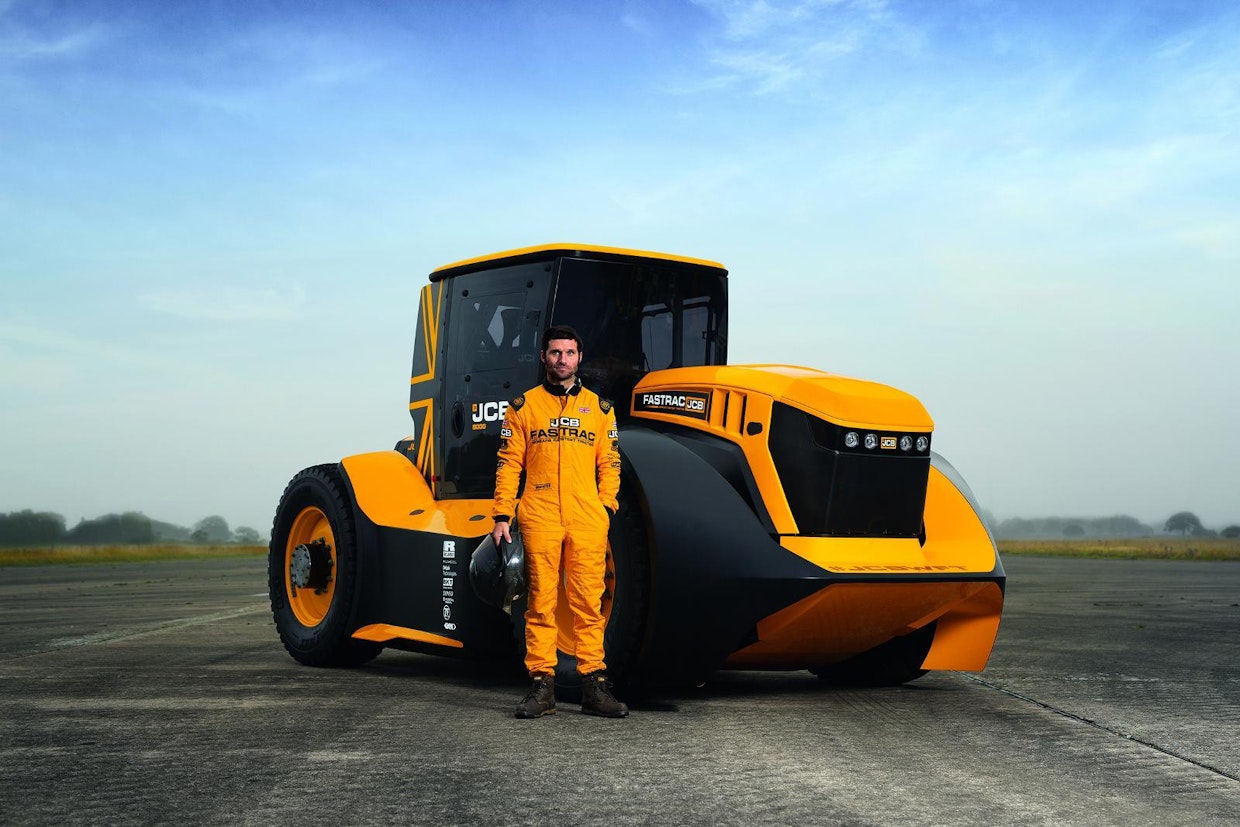 Kuvassa JCB Fastrac 8000 -ennätystraktorin vieressä seisoo ennätyksen ajanut kuljettaja Guy Martin.