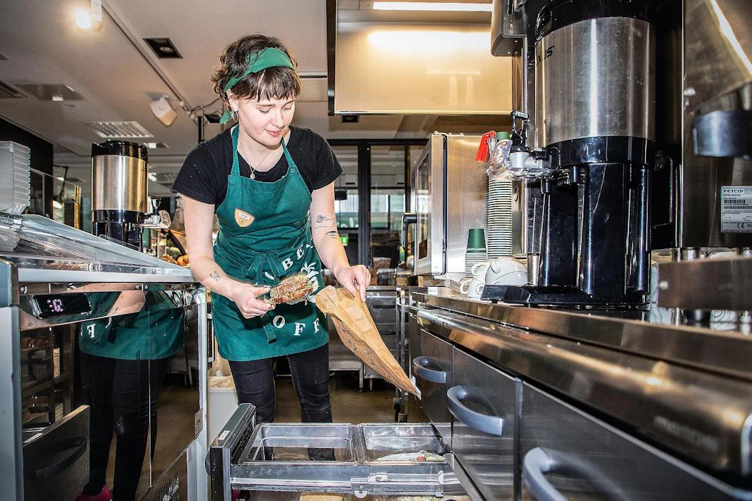 Chloe Ashworth pakkaa ResQ ruokaa Robert's Coffeessa Helsingissä. Sovellus on vähentänyt kahvilan myytävien tuotteiden hävikin lähelle nollaa.
