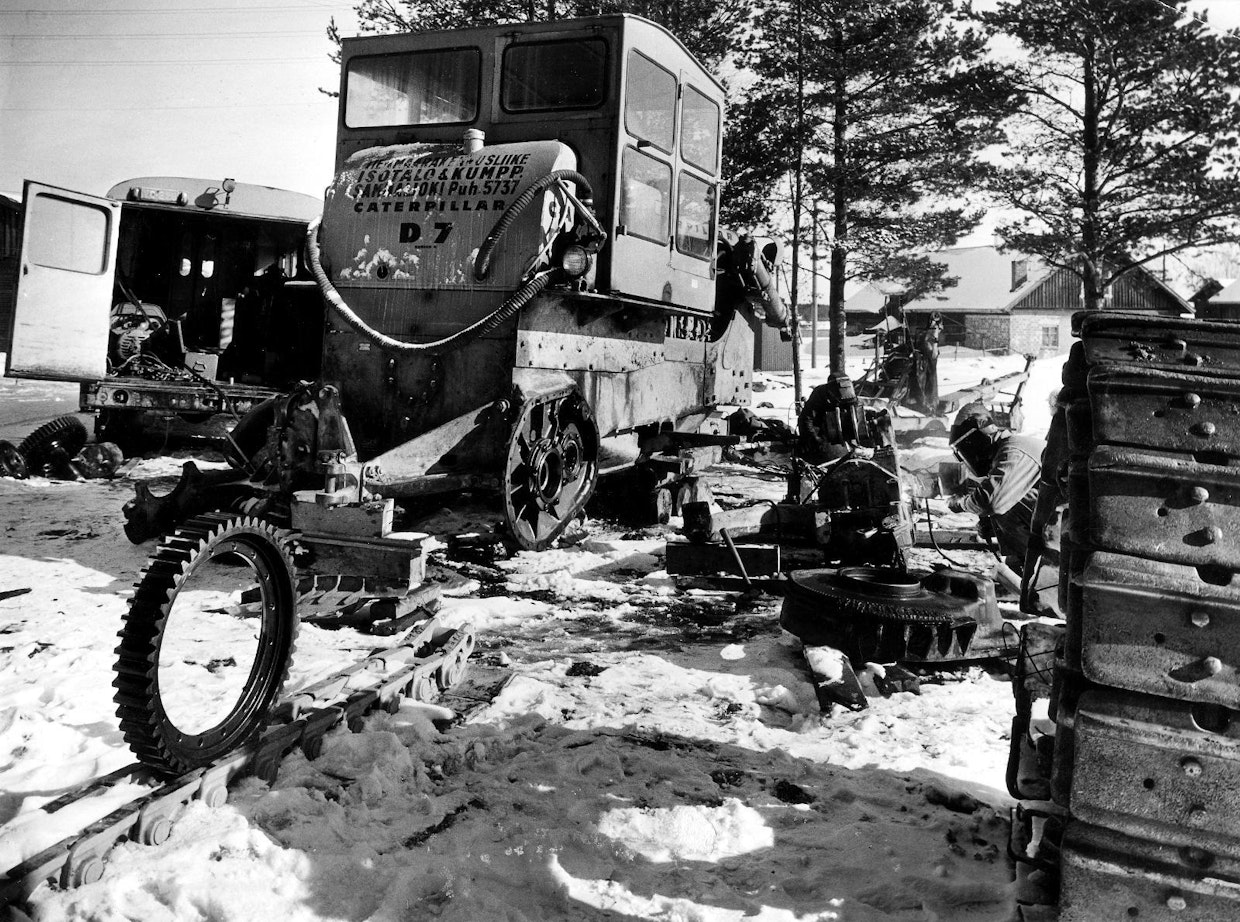 Talvinen huoltotyö menossa Sammaljoella vuonna 1961. Isotalo & Kumppaneiden CAT D7:n telarunko saa parhaillaan uutta hitsisaumaa. Vieressä olevaan vetokoteloon on jo tehty täytehitsaukset. Isotkin korjaukset tehtiin yleensä työmaalla tai asiakkaan luona säästä ja vuodenajasta riippumatta. Kuljetuskalustoa suurten koneiden siirtoihin oli vähän, joten konetta ei yleensä siirretty korjaamolle kesken työn. Korjaajan eli piirihuoltomiehen oli lähdettävä koneen luokse.