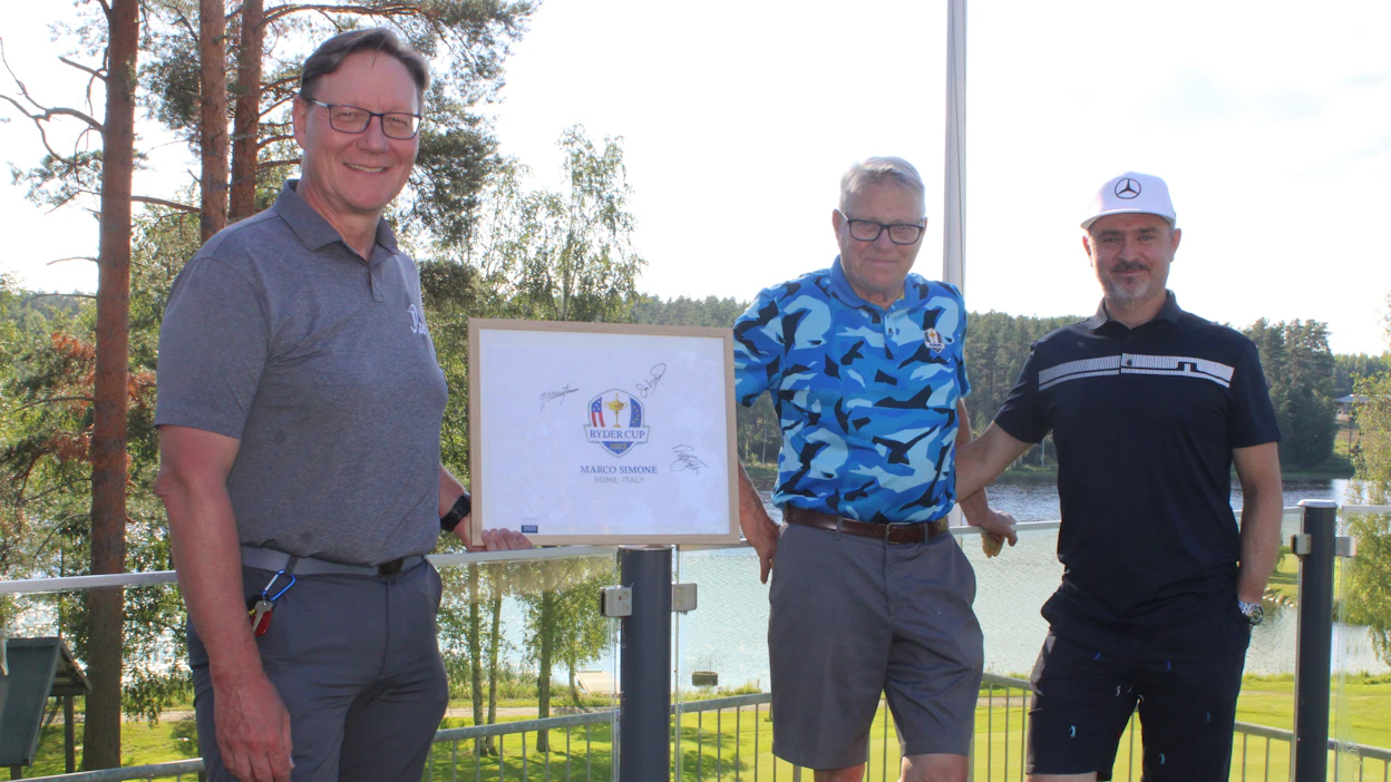 JGS:n toiminnanjohtaja Keijo Keskinen (vas.), teollisuusneuvos Esa Rannila sekä ammattilaisgolfari Mikko Korhonen olivat tyytyväisiä huutokaupan tulokseen. Kuvassa harvinainen golfin Ryder Cupin lippu nimikirjoituksilla.
