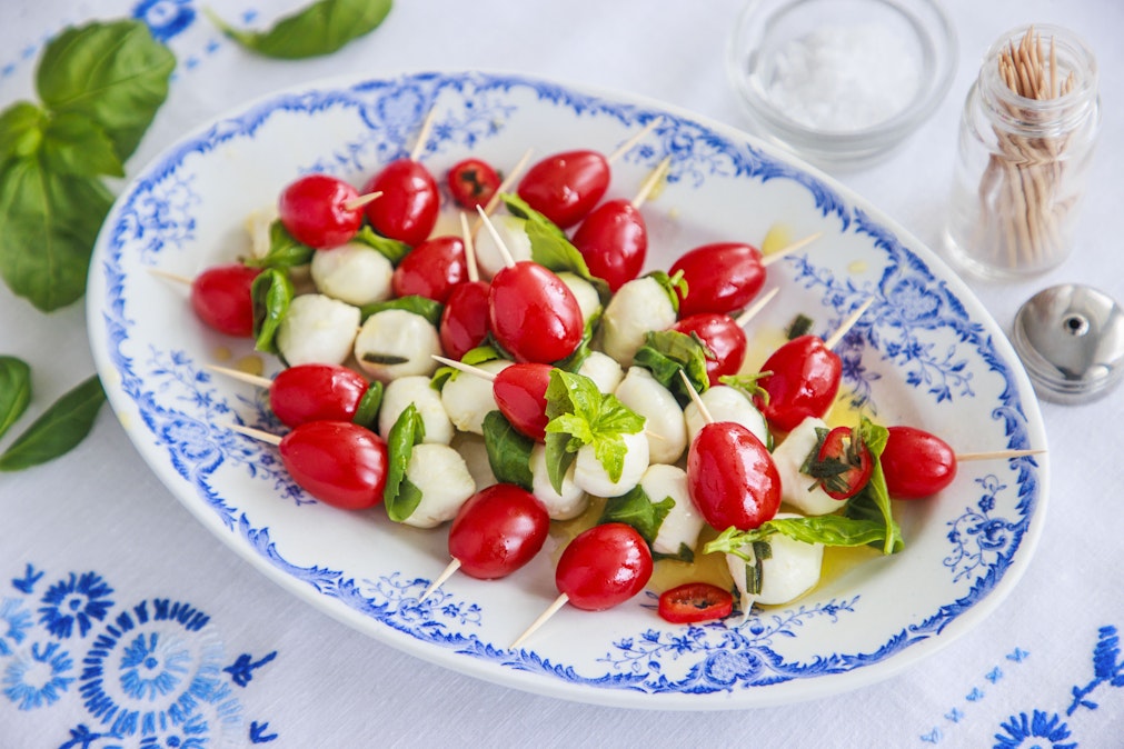 Tikkuun työnnetyt marinoidut minimozzarellapallot, kirsikkatomaatit ja basilikanlehdet vievät jo värien puolesta Italiaan.