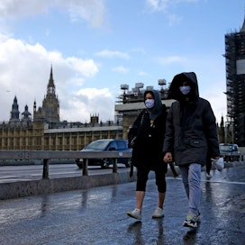 Hengityssuojaimin varustautuneita jalankulkijoita Westminsterin sillalla parlamenttitalon edustalla Lontoossa. LEHTIKUVA/AFP