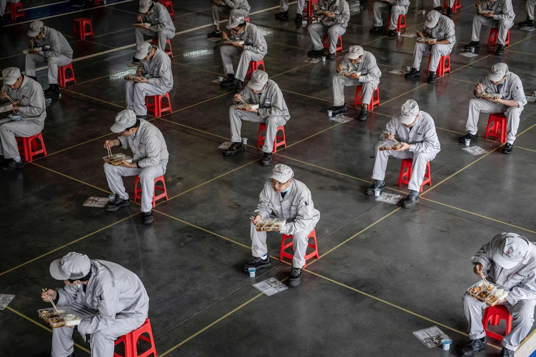 Autotehaan työntekijöitä lounaalla Kiinan Wuhanissa maaliskuun lopussa. LEHTIKUVA/AFP