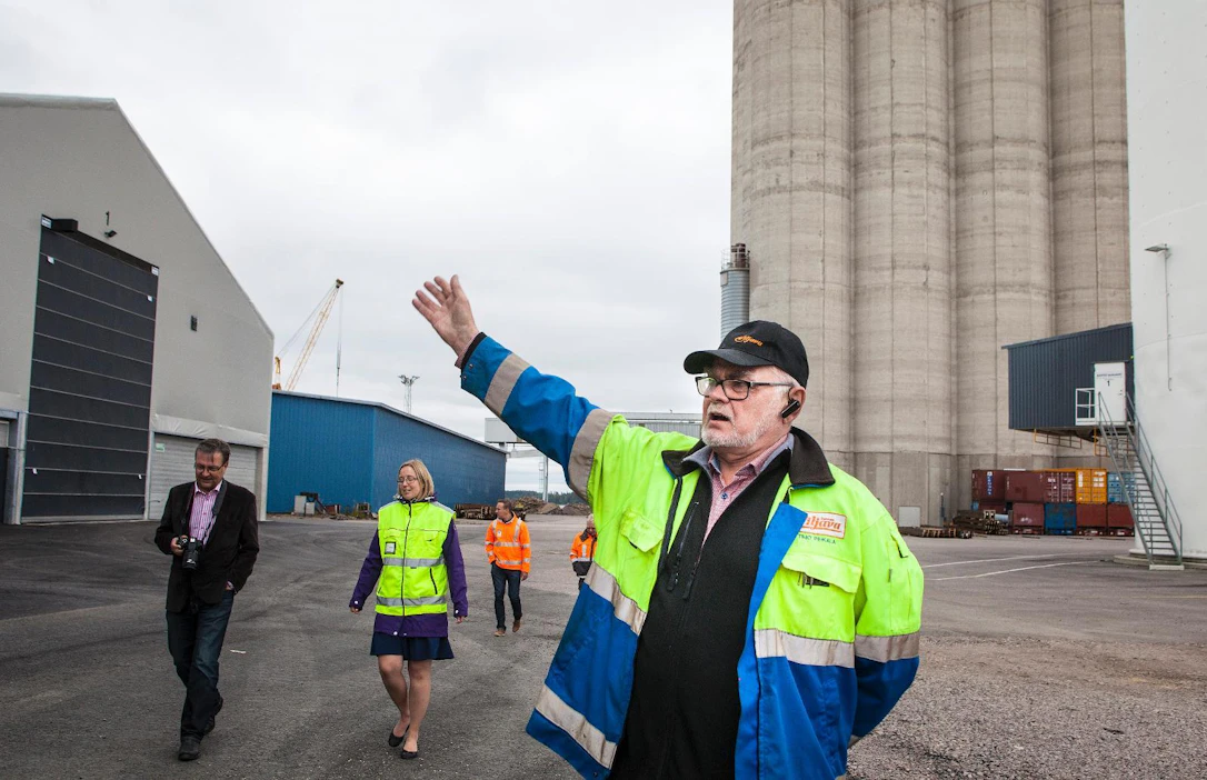 Siinä se on, uusi tasovarasto, osoittaa Suomen Viljavan kiinteistöpäällikkö Timo Pihkala. Taustalla näkyvät sataman 1980-luvulla valmistuneet, täydessä käytössä olevat betonisiilot. Pihkalan vasemmalla puolella keltaisissa huomioliiveissä Loviisan sataman toimitusjohtaja Tiina Vepsäläinen.