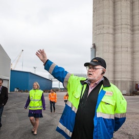 Siinä se on, uusi tasovarasto, osoittaa Suomen Viljavan kiinteistöpäällikkö Timo Pihkala. Taustalla näkyvät sataman 1980-luvulla valmistuneet, täydessä käytössä olevat betonisiilot. Pihkalan vasemmalla puolella keltaisissa huomioliiveissä Loviisan sataman toimitusjohtaja Tiina Vepsäläinen.