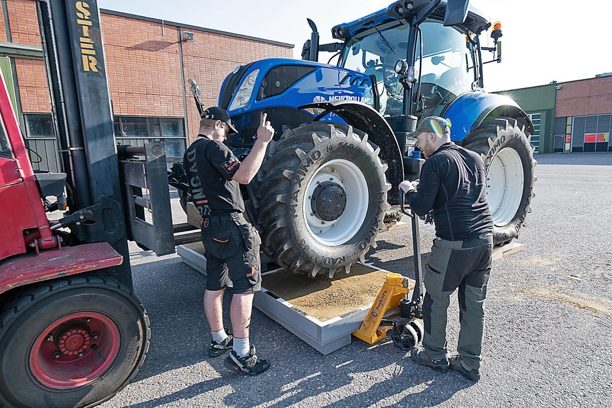 Hiekkalaatikkotestissä traktori nostettiin ilmaan trukilla. Traktori tasapainotettiin vanerilevyillä, jotta mittauksen aikana traktori oli vaakatasossa.