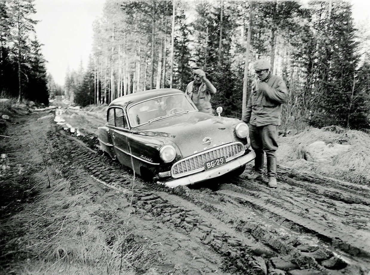 Voutilainen kuvasi myös monia erilaisia elämänilmiöitä maaseudulla kuvittamaan lehden julkaisemia uutisia. Tässä on kysymys kevään kelirikkoajasta huhtikuussa 1961. Opel on vajonnut akseleitaan myöten kuraan Vojakkalan–Topenontiellä Lopella.