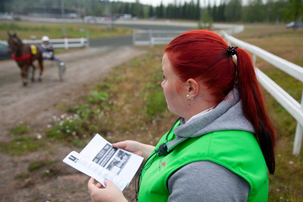 Heli Hyötyläinen varikkoalueen valvojan roolissa Kuopion raveissa. Kaikilla varikkoalueen toimihenkilöillä on radiopuhelin yhteydenpitoa varten.