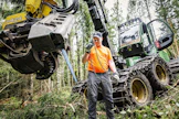 Yrittäjä Mikko Santajoki havainnollistaa, miten harvesteripään laipan ketjut irrotetaan.