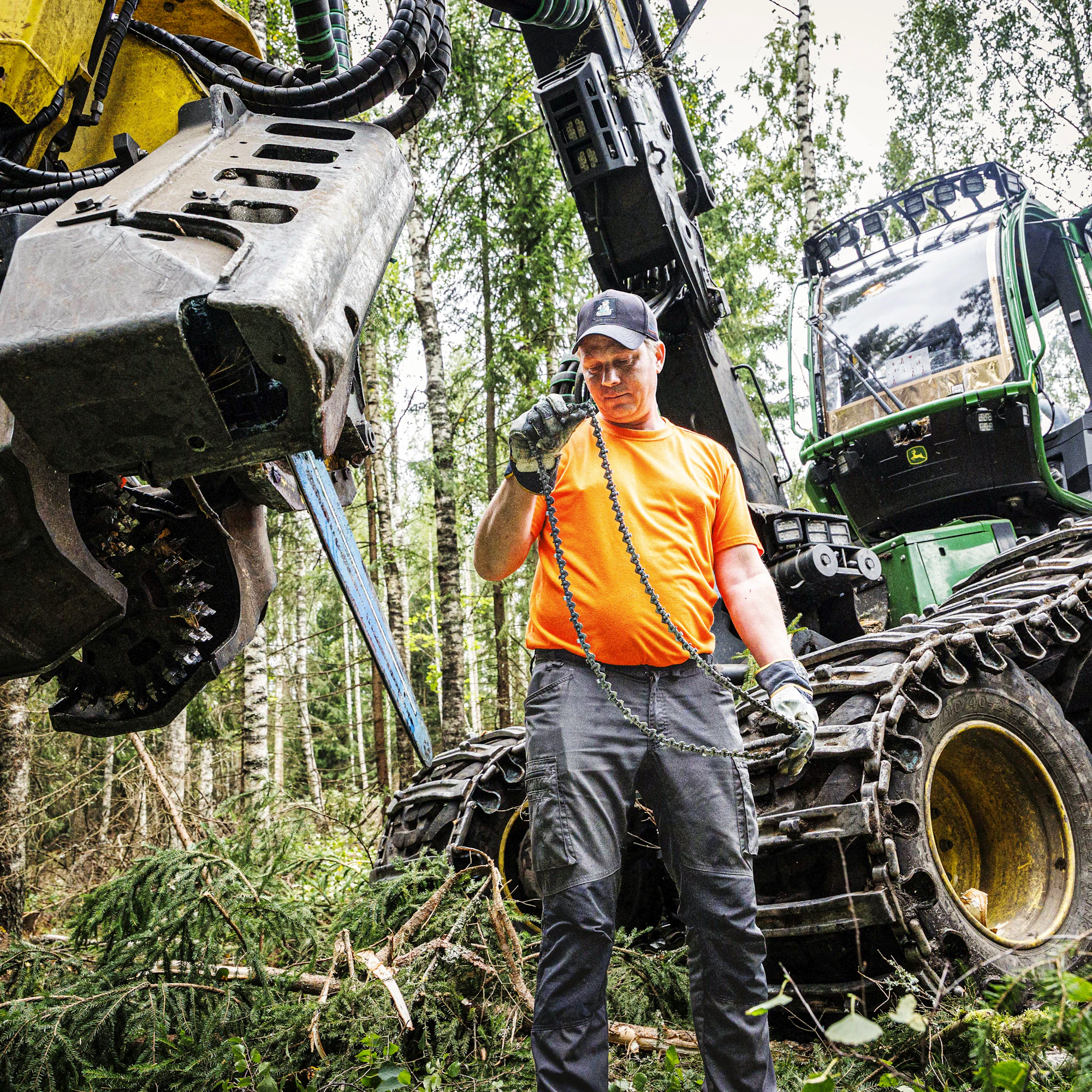 Yrittäjä Mikko Santajoki havainnollistaa, miten harvesteripään laipan ketjut irrotetaan.