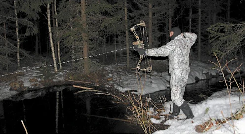 Nuoleen kiinnitetty kelalta purkautuva siima näkyy selvästi, kun Heikki Joskitt kohdistaa metsästysjousen veteen heitettyyn lumipalloon. Sami Karppinen