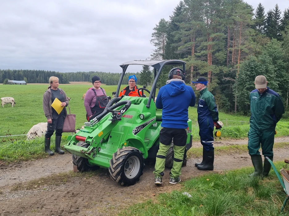 Piiroomäentilan Sari Rouvinen (oranssissa takissa keskellä) esitteli pienkuormaajan lomittajakilpailijoille ennen tehtävää.