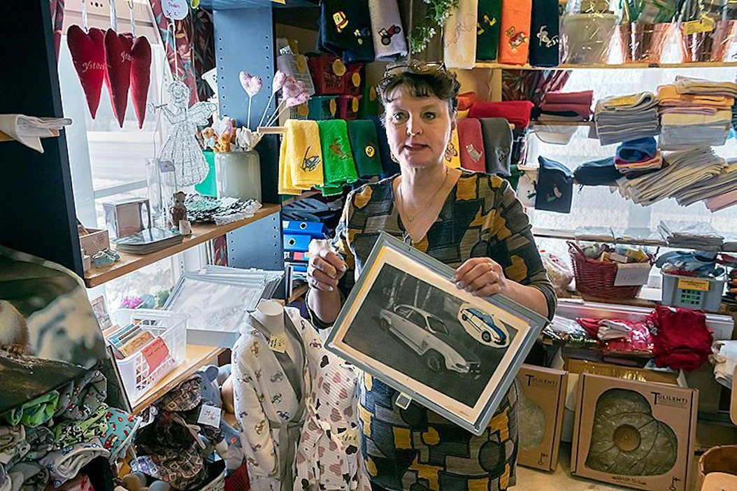 Anne Jaskari esittelee asiakkaan lähettämää Saab-kuvaa, josta tehtiin brodeeraus. Tilkkutäkin myymälästä löytyy monenmoisia käsitöitä.