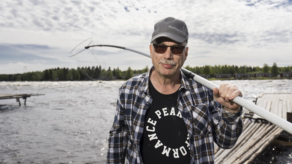 Markku Vaaraniemi pitää olallaan perinteistä lippoa. Taustalla pauhaa Kukkolankoski. Vastarannalla on Ruotsi.