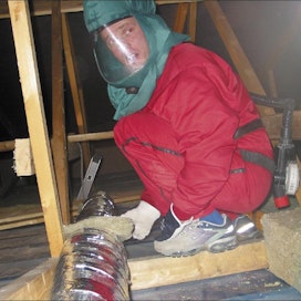 Aivo Leidik lämpöeristää pientalon yläpohjan ilmastointiputkia. Markku Vuorikari