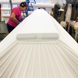 Usein suomalainen arkku on kangasverhoiltu. Kangas kiinnitetään käsityönä SHT-Tukun tehtaalla.