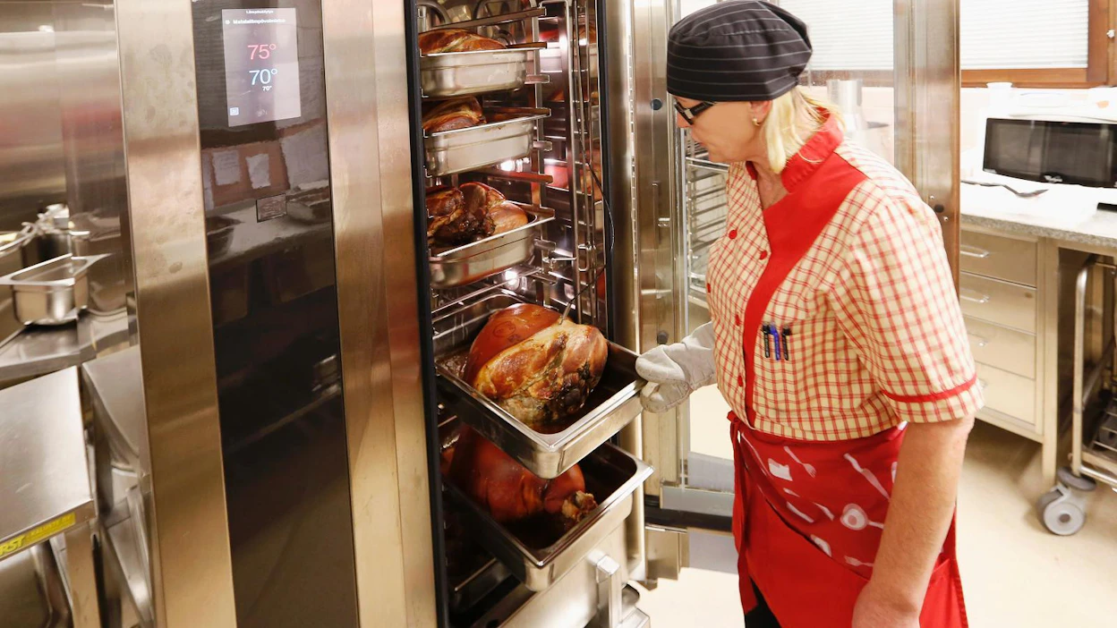 Sodankylän ruokapalvelupäällikkö Merja Ahola on kehittänyt kustannustehokkaan matalakypsennysmenetelmän lähiruuan valmistukseen. Airi Keränen valvoo kinkkujen kypsennystä.
